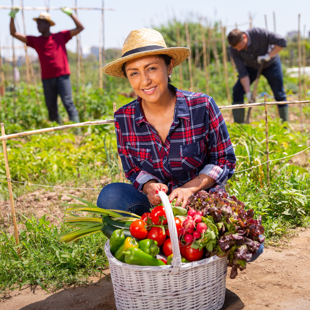 Smiling female agricultural worker with other agricultural workers.